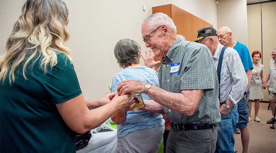 A group of older adults standing in line at an indoor event.