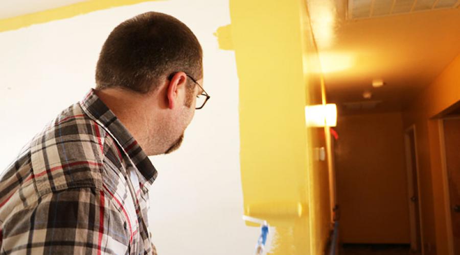 Man using roller to paint the edge of a wall