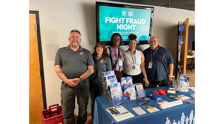 Five people standing behind a table with informational materials.