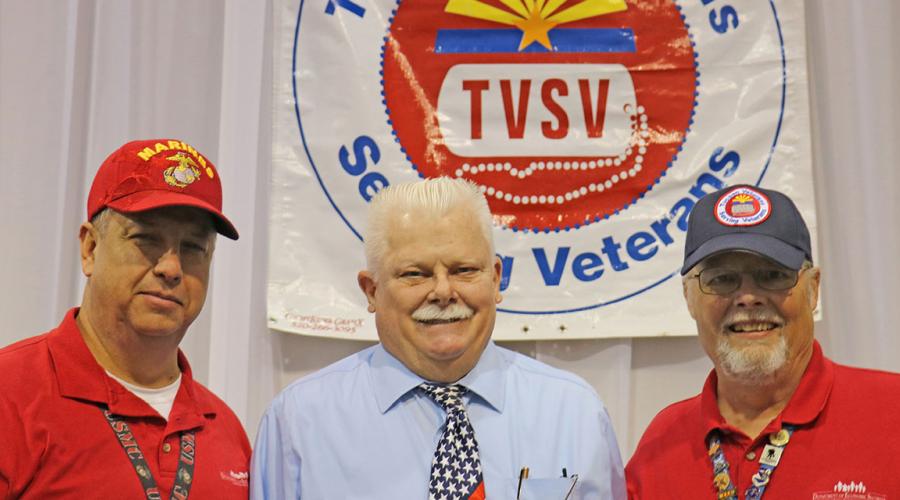three men stand before a banner that reads tucson veterans serving veterans