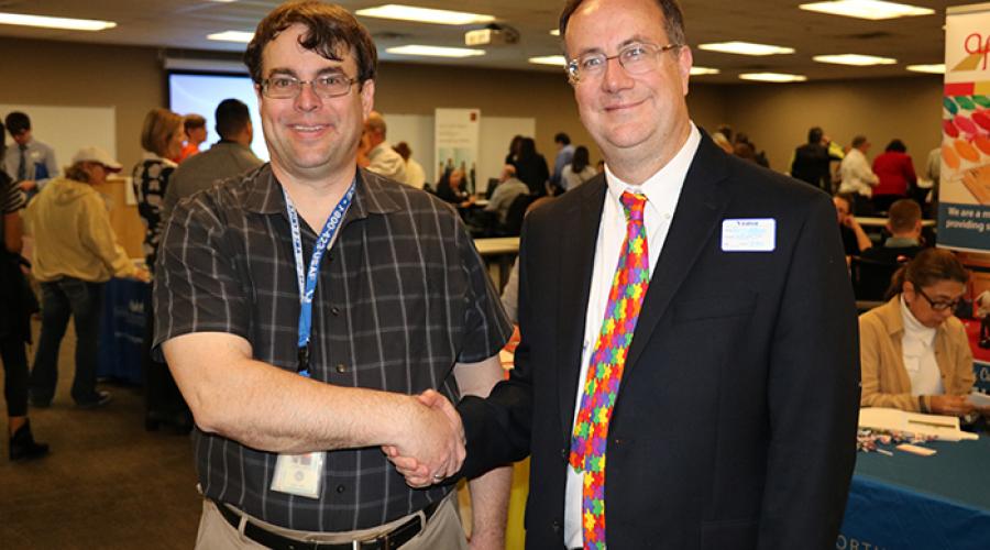 two men smile at the camera while shaking hands