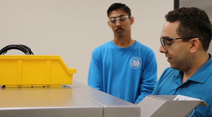 two men with safety goggles in front of industrial shredder