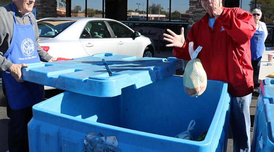 volunteers throwing frozen turkeys into a plastic bin