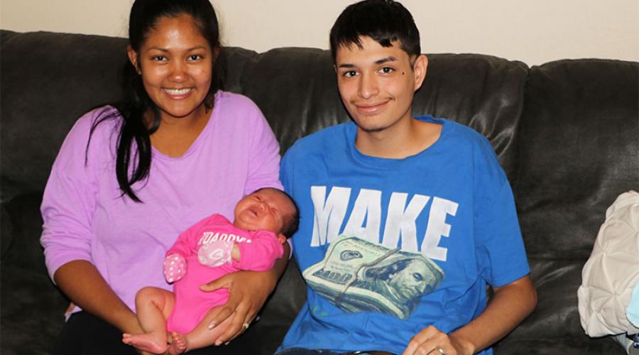 a young mother holds her newborn daughter while the young father sits beside her