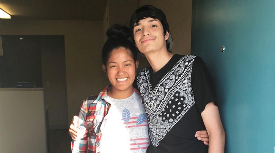 a young woman and man stand in doorway of an apartment