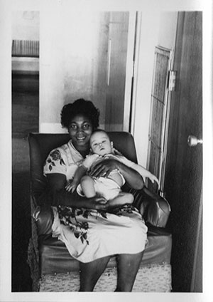 a woman sits in a sofachair, holding a baby