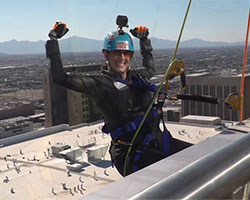 a woman wearing rappelling gear is about rappel down a skyscraper