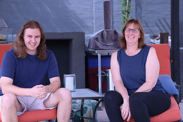 a young man and a woman sit on patio chairs