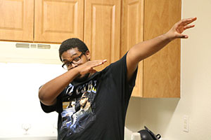Young man raises his arms in a “dab” of a dance move.