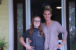 a young woman and older woman standing outside the front door of their home